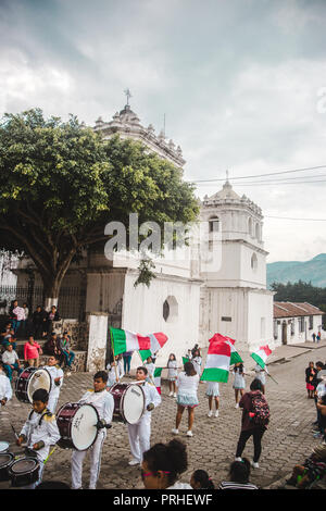 Mädchen winken italienische Flaggen folgen einer Blaskapelle in Ciudad Vieja, Guatemala Stockfoto