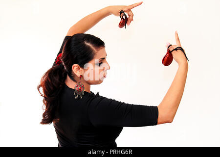 Junge Spanische gypsy woman dancing Flamenco mit braunen Kastagnetten in den Händen. Flamenco Tänzerin in schönen nationalen Kleid auf einem weißen Hintergrund. Spanien Stockfoto