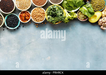 Super Essen oder vegetarisches Essen Konzept. Samen, Getreide, Bohnen, Gemüse, Kräuter für gesundes Kochen auf blauen Stein Hintergrund Draufsicht mit Kopie Raum Stockfoto