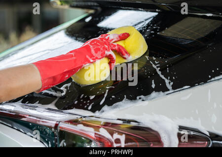 Hand mit Schwamm waschen Fenster eines Autos Stockfoto