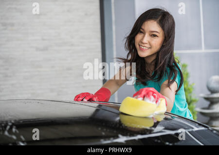 Frau waschen das Dach des Autos mit Schwamm Stockfoto