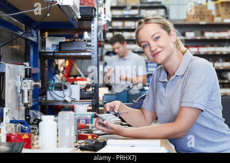 Portrait von Ingenieurin in der Factory Messen Komponente an der Werkbank mithilfe eines Mikrometers Stockfoto