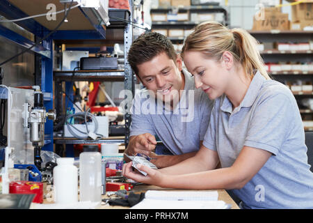 Ingenieur helfen weiblichen Lehrling im Werk mit Hilfe zu messen Komponente Mikrometer Stockfoto