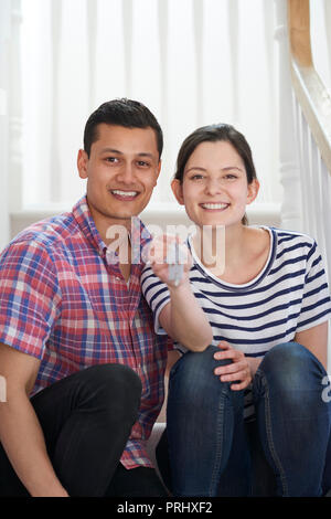 Porträt des jungen Paares auf Treppen Holding Schlüssel zu neuen Zuhause sitzen Stockfoto