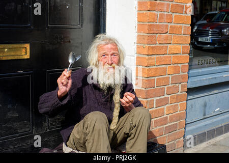 Ein Straßenmusiker seine Löffel spielen mit Hintergrundmusik auf der High Street in Wells, Somerset, Großbritannien Stockfoto