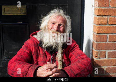 Ein strassenmusiker ist eine Pause und mit jemand auf der High Street in Wells, Somerset, UK Chat Stockfoto