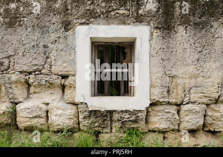 Fenster mit weißen Rahmen an der Wand der staubigen und rostigen Steine, alte Hintergrund mit alten Thema. Stockfoto