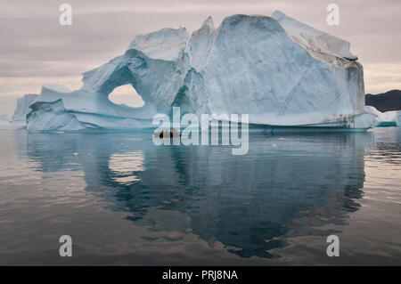 Touristen in aufblasbaren Boot vor Verwitterten Eisbergs, Scoresby Sund, Grönland Stockfoto