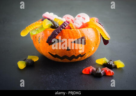 Natürliche Kürbis Jack mit Halloween verschiedene Süßigkeiten auf schwarzem Hintergrund Stockfoto