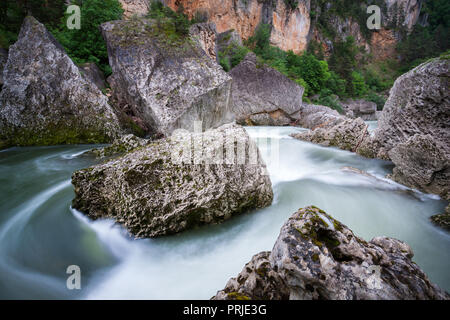 Schnell fließenden Wasser um riesige Felsbrocken und Fluss Steine in den Gorges du Tarn Aveyron Frankreich Stockfoto