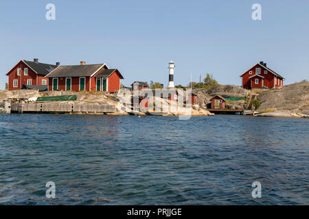 Rote Holzhäuser mit Leuchtturm an der felsigen Küste, Stockholmer Schären, Huvudskär Archipel Insel, Schweden Stockfoto