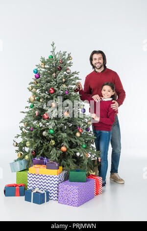 Gerne Vater mit Tochter schmücken Weihnachtsbaum mit Geschenken isoliert auf weißem Stockfoto