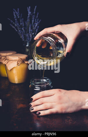 7/8 Bild der Frau Honig in jar auf schwarzem Hintergrund gießen Stockfoto