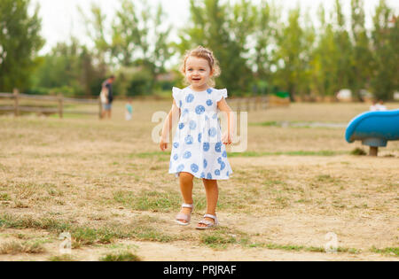 Hübsches kleines Mädchen mit blondem Haar und blauen Augen spielt im Freien im Sommer. Stockfoto