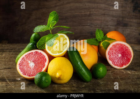Von rohem Obst und auf hölzernen Hintergrund ausschneiden, wie eine Zitrone, Grapefruit, Orange, Minze, Gurke und Ingwer Stockfoto