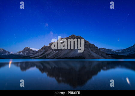 Die hellen Planeten Mars (rötlich) und Jupiter (rechts, über Bug Gletscher) über Bow Lake, Banff, Alberta, und im Wasser in Glitter p widerspiegelt Stockfoto