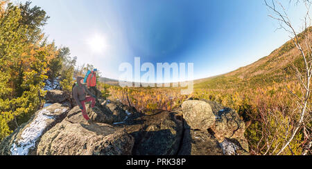 Paar Touristen mit Rucksäcken Mann und Frau, die auf einem Felsen im Herbst Wald panorama Stockfoto