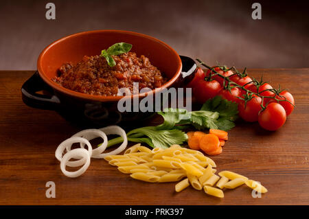 Penne-Nudeln in Tomatensauce mit Huhn, Tomaten mit Petersilie auf einem Holztisch dekoriert Stockfoto