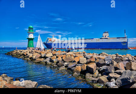 Leuchtturm mit Passagierschiff auf der Ostsee an der Hafeneinfahrt, Warnemünde, Deutschland Stockfoto