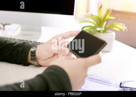 Business Mann, Telefon in der Hand mit Computer und Papier. Stockfoto