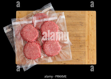 Isolierte Beef Burger Pastetchen vorbereitet, die für das Einfrieren Vakuum im klaren Kunststoff bereit für Sous-vide Garen in einem Top-down-Sicht auf ein Holzbrett auf Stockfoto