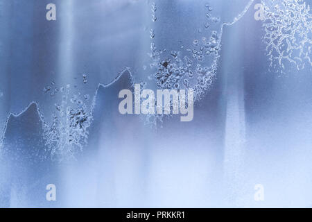 Wellenförmige bizarr diagonal frosty Muster auf blau gefroren Winter Fenster. Stockfoto