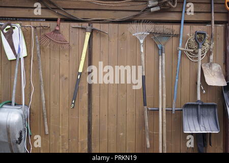 Schaufeln rechen Hämmer hängen an die Holzwand Stockfoto