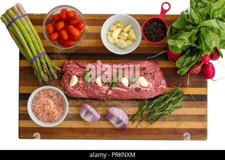 Ansicht von oben Der gewürztes Fleisch neben Gemüse wie Tomaten und Basilikum auf Schneidebrett Stockfoto