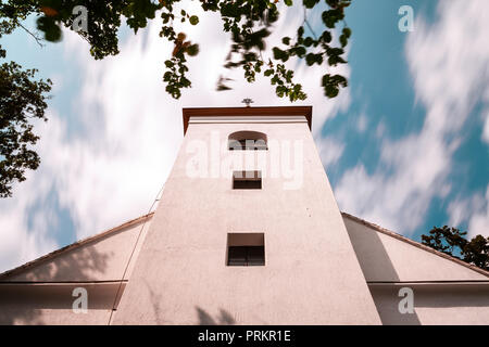 Eine einfache weiße Kapelle von unten mit ziehenden Wolken. Lange Belichtung geschossen. Stockfoto