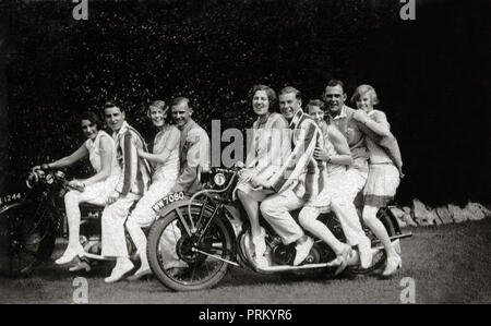 Stellen Gruppe von neun glückliche Damen, Mädchen & Gentleman für Fotografie auf zwei Oldtimer Motorräder in den 1920er Jahren Stockfoto