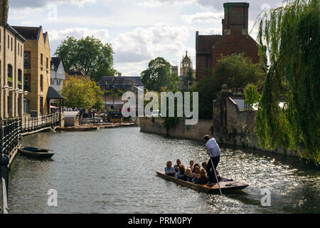 Ein punt Boot mit mehreren Personen an Bord auf dem Fluss Cam Position zu Magdalena Brücke an einem sonnigen Nachmittag, Cambridge, Großbritannien Stockfoto