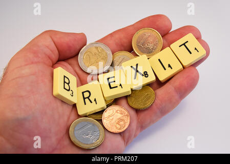 Hand mit Euro-bargeld und Brexit Schriftzug in Scrabble Fliesen auf weißem Hintergrund. Europäische Union Volksabstimmung zu verlassen, Politik Stockfoto