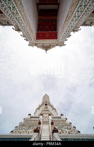 Von unten Blick auf den wunderschönen Wat Arun Tempel mit gemusterten Wänden auf dem Hintergrund der bewölkten Himmel Stockfoto