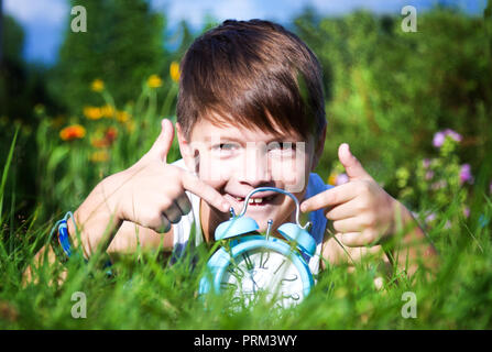 Junge mit Wecker im Sommer Garten Stockfoto