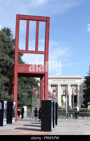 Genf, Schweiz - Oktober 1, 2017: kaputter Stuhl und Palast der Nationen in Genf. Kaputter Stuhl ist eine monumentale Skulptur in Holz Stockfoto