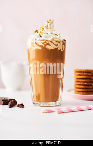 Schokolade Eis Kaffee mit Sahne und Cookies in ein hohes Glas mit rosa Strohhalme auf weißem Marmortisch über rose Hintergrund. Hochauflösendes Bild Stockfoto