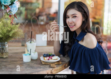 Junge Frau essen blueberry Käse Kuchen im Cafe Stockfoto