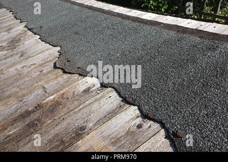 Eine abgenutzte, beschädigte Gartenhaus Dach reparaturbedürftig. Stockfoto