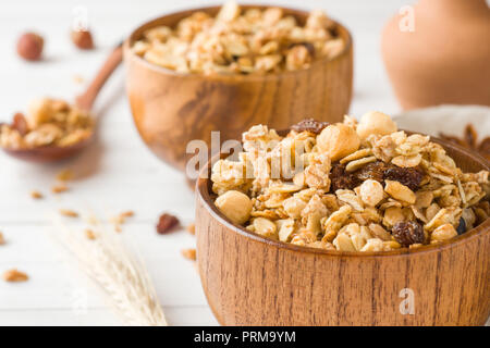 Trockene Frühstück der Hafer Flocken, Granulat und Muttern. Müsli in eine Tiefe hölzerne Platte Stockfoto