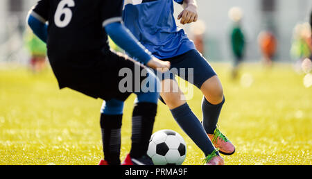 Fußball-Spieler in Aktion ausgeführt wird. Fußballspiel. Jungen Fußball-Spieler Laufen mit dem Ball. Jungs kicken Fußball-Ball. Fußball Jugend Mannschaften spielen Außend Stockfoto