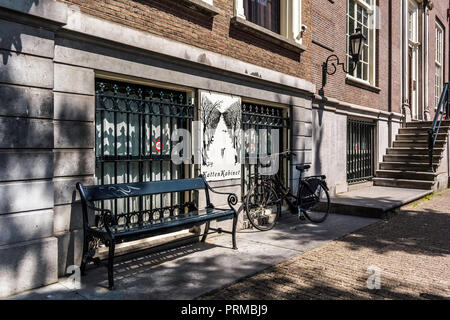 Schwarze Sitzbank und Fahrrad im Windows und Zeichen des KattenKabinet (Cat) Museum. Stockfoto