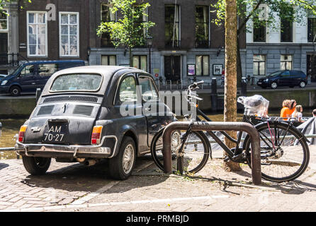 Rückseite der Schwarzen alten rostigen Italienische Kleinwagen Fiat 500 L oder lusso an einer der Amsterdamer Grachten geparkt Stockfoto