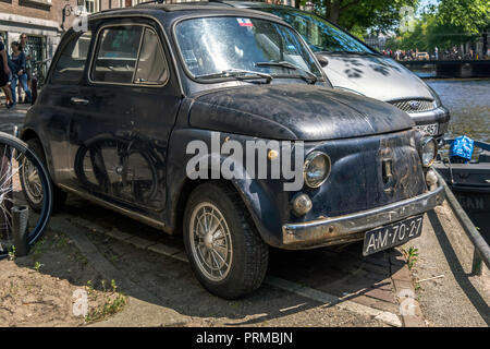 Vorderseite der schwarzen alten rostigen Italienische Kleinwagen Fiat 500 L oder Lusso in der Nähe der Grachten von Amsterdam geparkt. Stockfoto