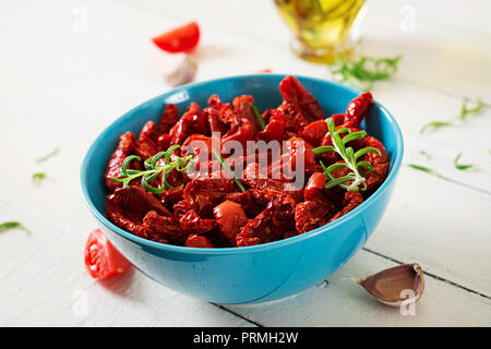 Sonnengetrocknete Tomaten mit Kräutern und Knoblauch in der Schale auf Holztisch. Italienisches Essen. Stockfoto