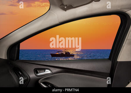 Blick aus dem Seitenfenster des Autos auf der wunderschönen Meereslandschaft mit Boot Stockfoto