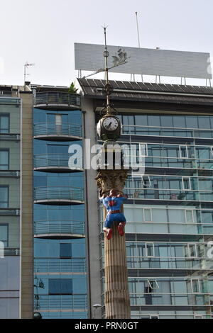 Spider-man Figur klettert einen Obelisk mit Uhr und Windfahne. A Coruña Comic-Con, Spanien. Stockfoto