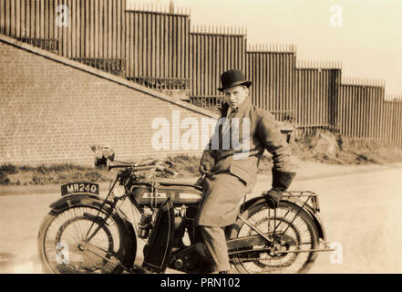 Gentleman trägt eine Melone, saß auf seinem 1922 BSA 350 ccm Seite Ventil Motorrad, vor einer Mauer und Zäune in den 1920er Jahren Stockfoto