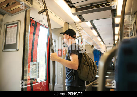 Touristische Mann oder Student mit einem Rucksack warten auf den Zug zu stoppen, nach draußen zu gehen. Stockfoto