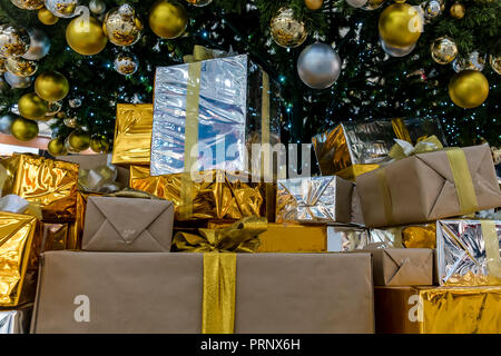 Viele Weihnachtsgeschenke auf dem Boden unter dem Tannenbaum. Geschenk in glänzendem Gold Verpackung auf dem Boden liegend unter dem Baum. Geschenke vom Weihnachtsmann. Stockfoto