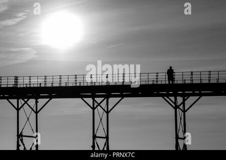 Monochrome einzelner Mann denken auf einem alten englischen Victorian seaside Pier Stockfoto